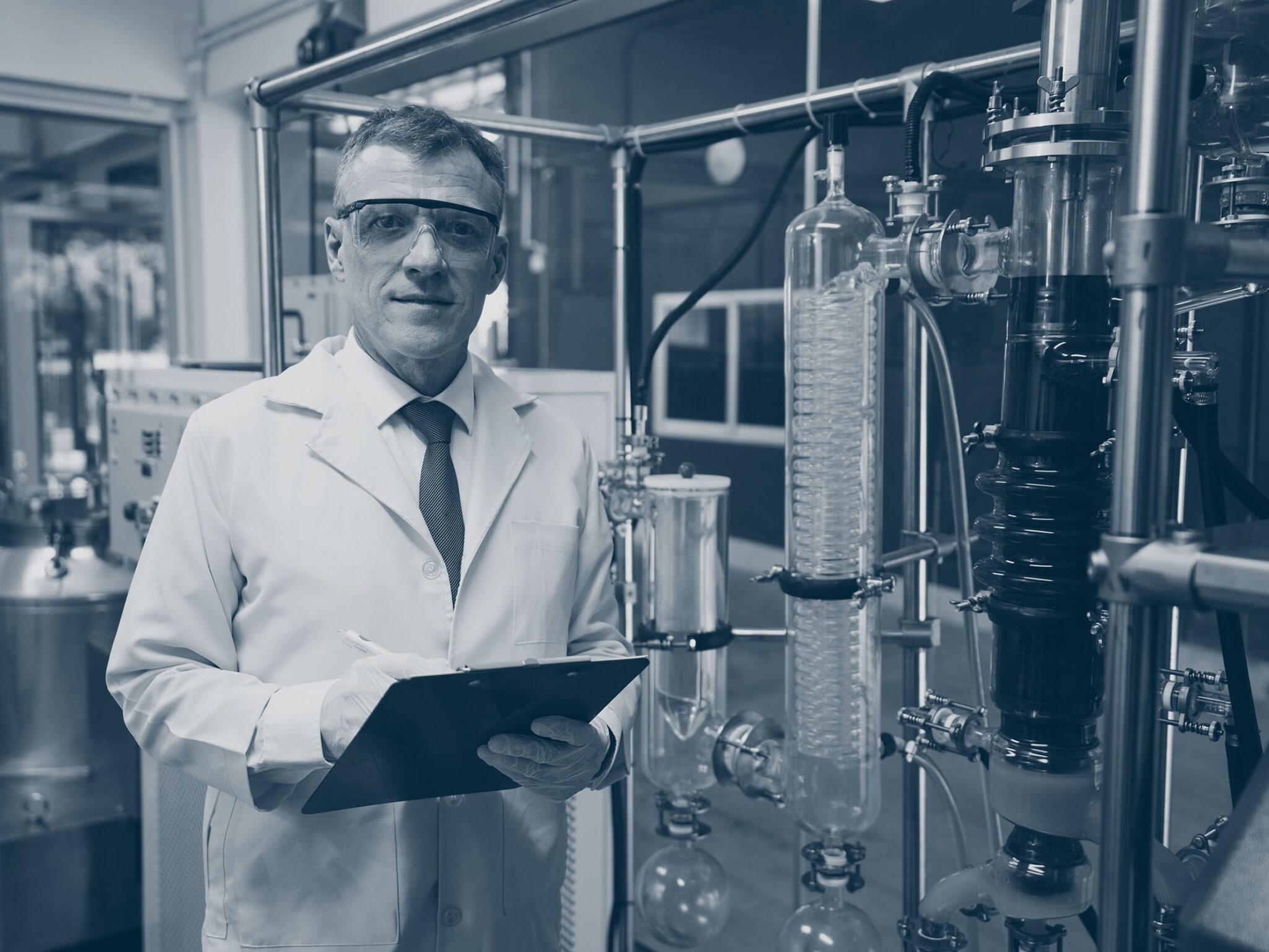 Portrait of Caucasian expert cannabis researcher in lab uniform checking rotational vaporizer machine in process of CBD oil extraction. Shot of male scientist looking at camera with confident face.